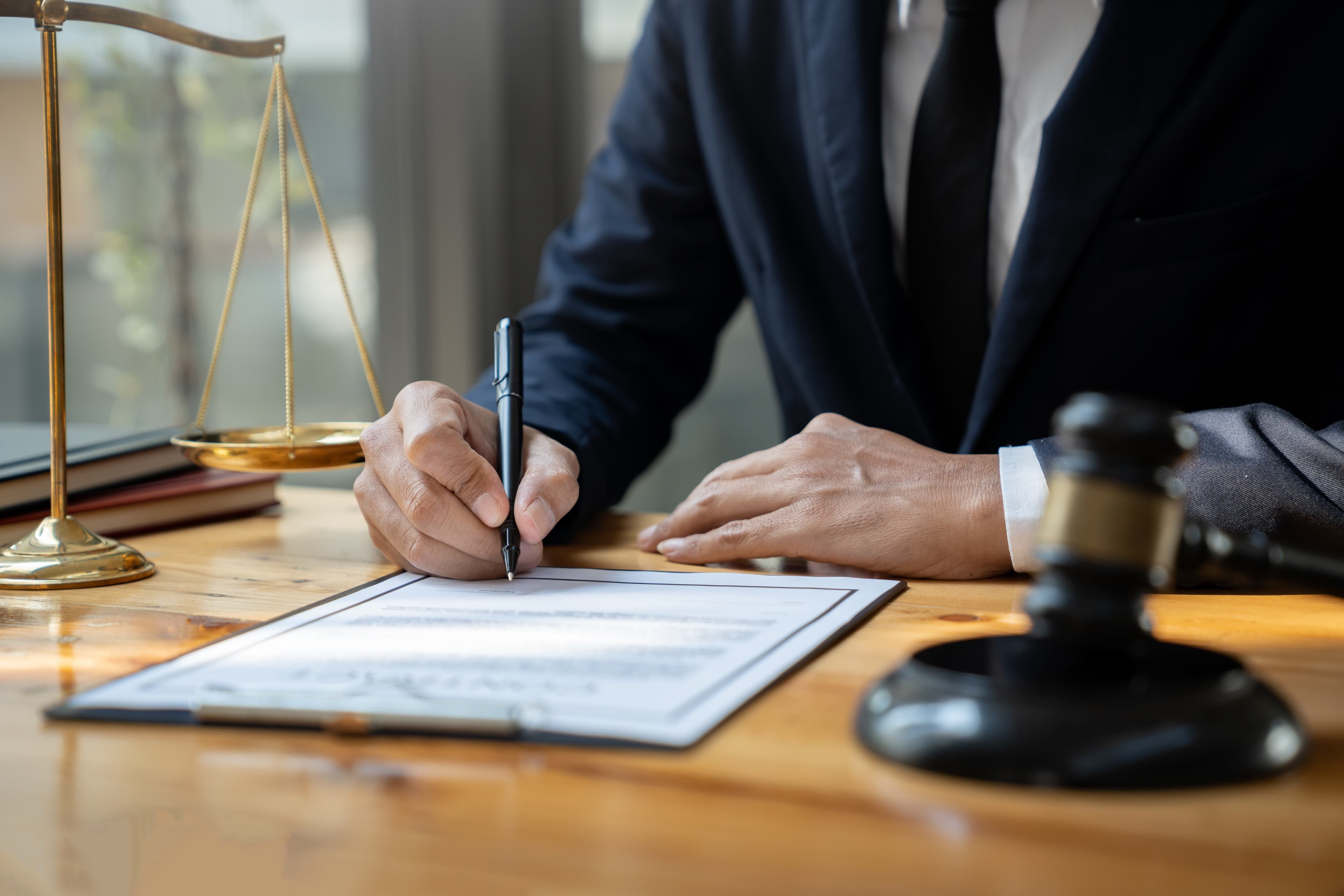 Professional PAT testing service provider signing compliance documents with scales of justice in the background, indicating legal certification for electrical safety testing.