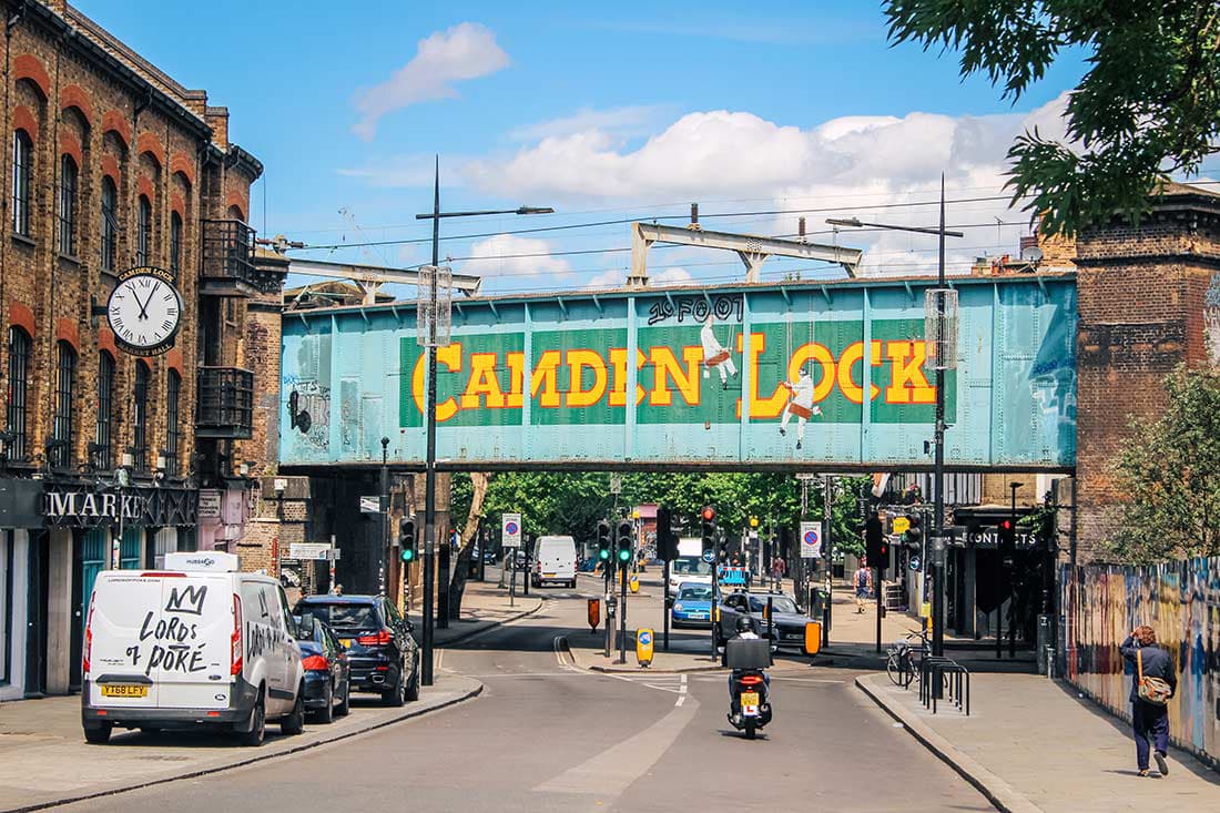 Vibrant view of the iconic Camden Lock Bridge in Camden Town, North London, featuring the colorful Camden Lock signage, bustling street traffic, and historic buildings, capturing the eclectic and lively atmosphere of this popular cultural district.
